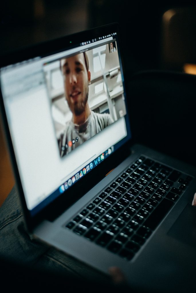 A laptop screen lights up a dark room with a video call. This could represent online depression therapy in Sacramento, CA. Contact an online therapist for more information about online depression therapy and other services.