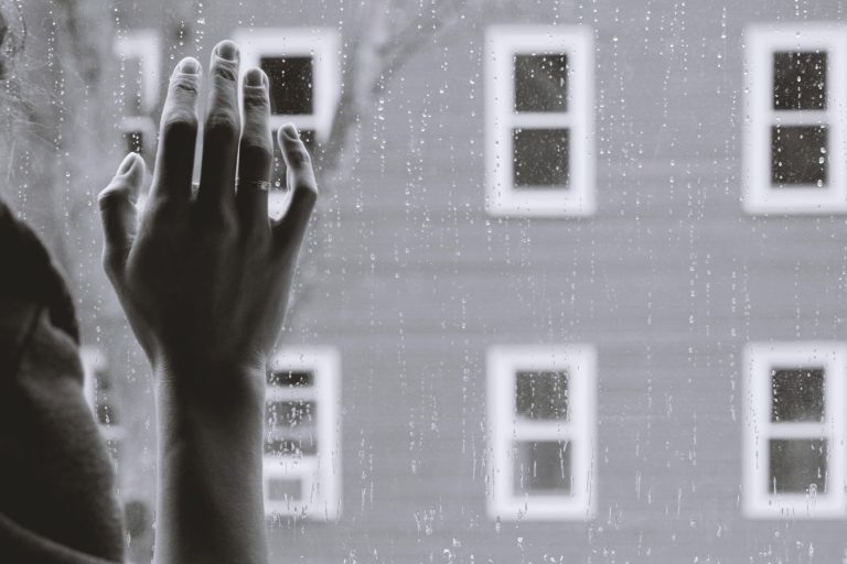 A hand rests against a rain covered window, representing the isolation of depression. Contact a depression therapist in PSacramento, CA for support with depression treatment in Sacramento, CA. We offer online depression therapy California and other services. 95814 | 95688 | 95765