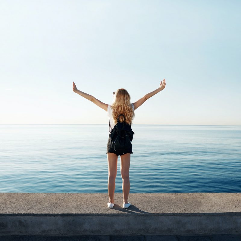 A woman extends her arms joyfully as she stands next to the ocean. This bright photo could represent overcoming trauma with a trauma therapist in Pasadena, CA. Contact a trauma therapist in Sacramento, CA for more information on PTSD treatment in Pasadena, CA and other services. 95814 | 95688 | 95765